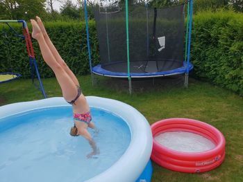 Full length of girl doing handstand in wading pool