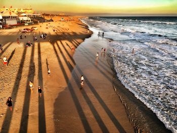 High angle view of people on shore at beach during sunset