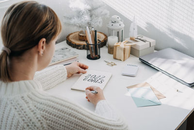 2022 goals, new year resolution. woman in white sweater writing text 2022 goals in open notepad on
