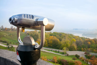 Close-up of machine part on landscape against sky