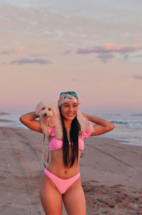 Portrait of young woman in bikini standing at beach