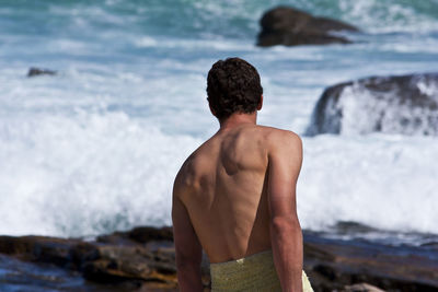 Rear view of shirtless man standing at beach