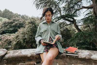 Portrait of young woman sitting on tree trunk