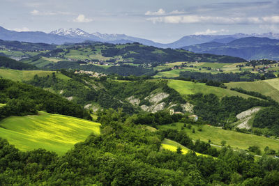 Scenic view of green landscape and mountains against sky