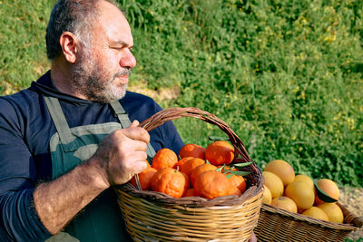 Farmer holding a crate with ripe natural organic citrus fruit.