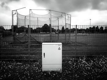 Electric box by playing field against sky