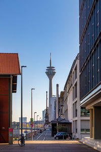 Cars on road by buildings against clear sky