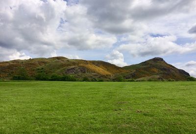 Arthur's seat hill with green grass against cloudy sky