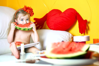 A 3 year old girl eats a watermelon.