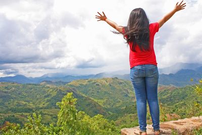 Rear view of woman with arms outstretched against mountains