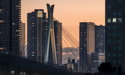 Modern buildings in city against sky during sunset