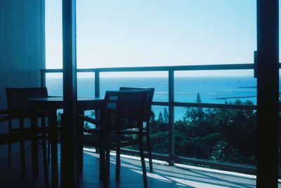 Chairs and table by sea against sky
