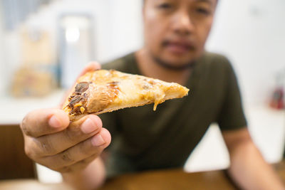 Close-up of hand holding pizza