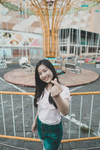 Portrait of smiling young woman standing against building