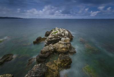 Scenic view of rocks in sea against sky