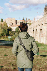 Rear view of young man standing on grassy field