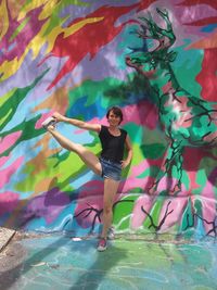 Full length of woman standing against multi colored water