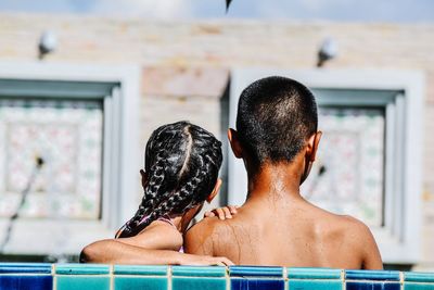 Rear view of shirtless boy with sister at swimming pool