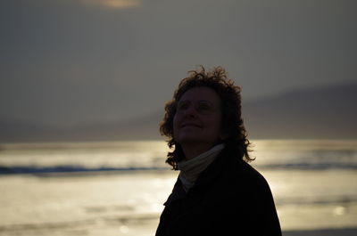 Smiling woman at beach against sky