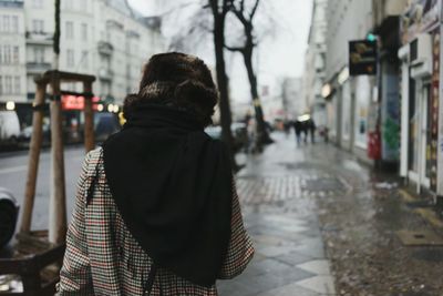 Rear view of woman holding umbrella in city