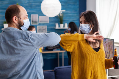 Man and woman wearing mask doing elbow bump