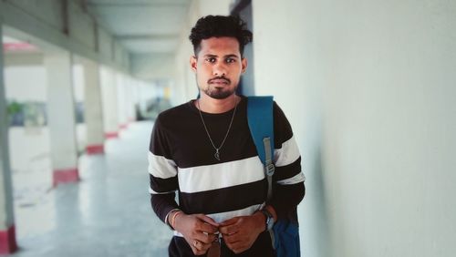 Portrait of young man standing near wall