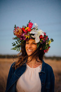 Portrait of smiling young woman standing on field against sky