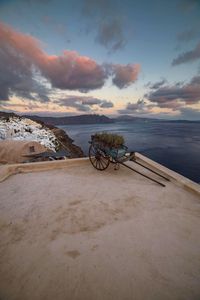 Push cart on building terrace by sea against sky