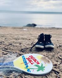 Close-up of shoes on sand at beach