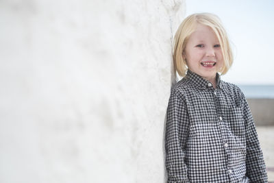 Portrait of smiling boy standing by wall