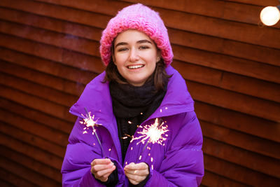 Caucasian girl is having fun in winter on street with sparklers in her hand