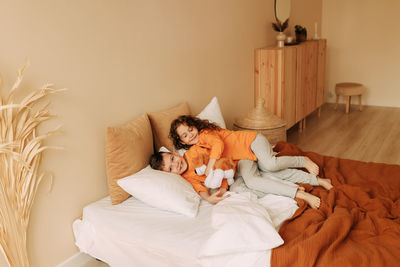 Funny happy kids brother and sister in pajamas playing having fun in a cozy bedroom at home