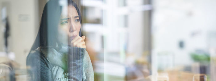 Side view of woman looking through window