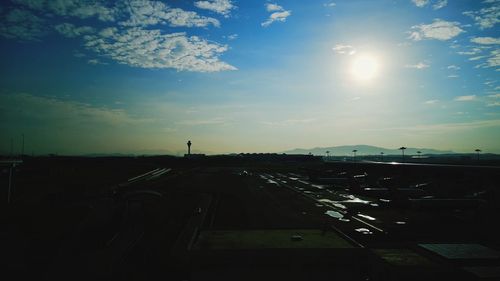 Vehicles on road against sky during sunset