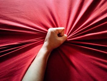 Cropped hand holding red bed sheet