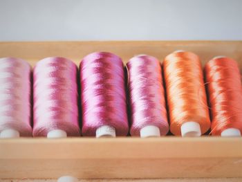 Close-up of multi colored thread spools in wooden container