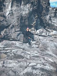 Full length of young man sitting on rock