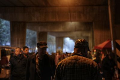 Rear view of people standing against wall