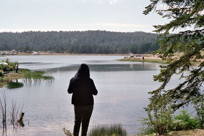 Rear view of woman looking at lake against sky