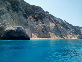 Scenic view of sea and mountains against clear blue sky