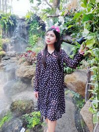 Portrait of young woman standing against waterfall