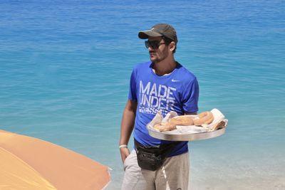 Full length of man looking away while standing at blue sea