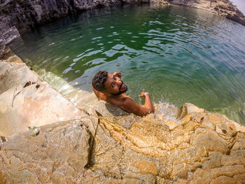 High angle view of young man relaxing on rock