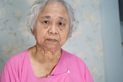 Portrait of senior woman against wall