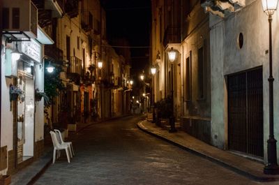 Illuminated street amidst buildings at night