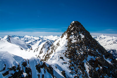 Scenic view of snowcapped mountains against blue sky