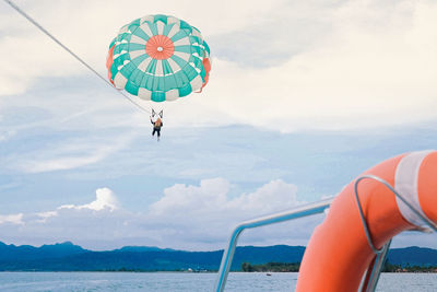 Low angle view of person parasailing over sea against sky