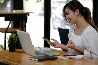 Young woman using smart phone on table
