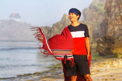 Full length of smiling young man standing on beach