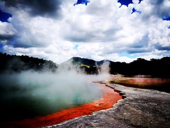 Scenic view of waterfall against cloudy sky